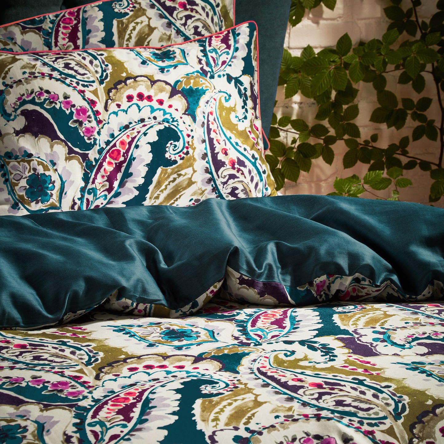 Close up of the luxury Aretha Paisley Pattern Duvet Cover Bed set with a dark on one half of the bed showing the duvet folded over revealing the reversible underside with a soft green sheen.