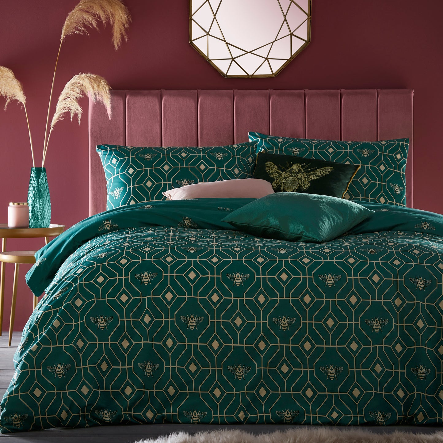 Beautiful luxury duvet cover bedding set with a geometric pattern and small bees in each geometric shape, burgundy red headboard and sliver accent mirror above on the wall. Bedding is in a dark emerald colour.