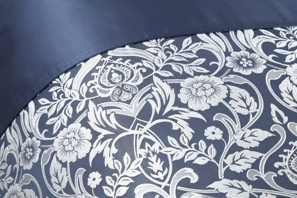 Close up of double bed duvet set displaying the Harrow Collection Embellished Jacquard Duvet Double Bedding Cover Set in Navy Blue with a silver satin embroidery finish. Delicate floral design and top of duvet is turned over to show the plain navy satin finish. 