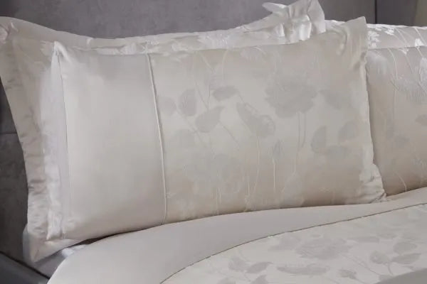 Close up of double bed with grey headboard from a side view showing one half of the bed displaying the Meadows Collection Embellished Jacquard Duvet Double Bedding Cover Set in Cream. Sateen sheen on one third of the pillow and the remainder showing a delicate butterfly and floral pattern.