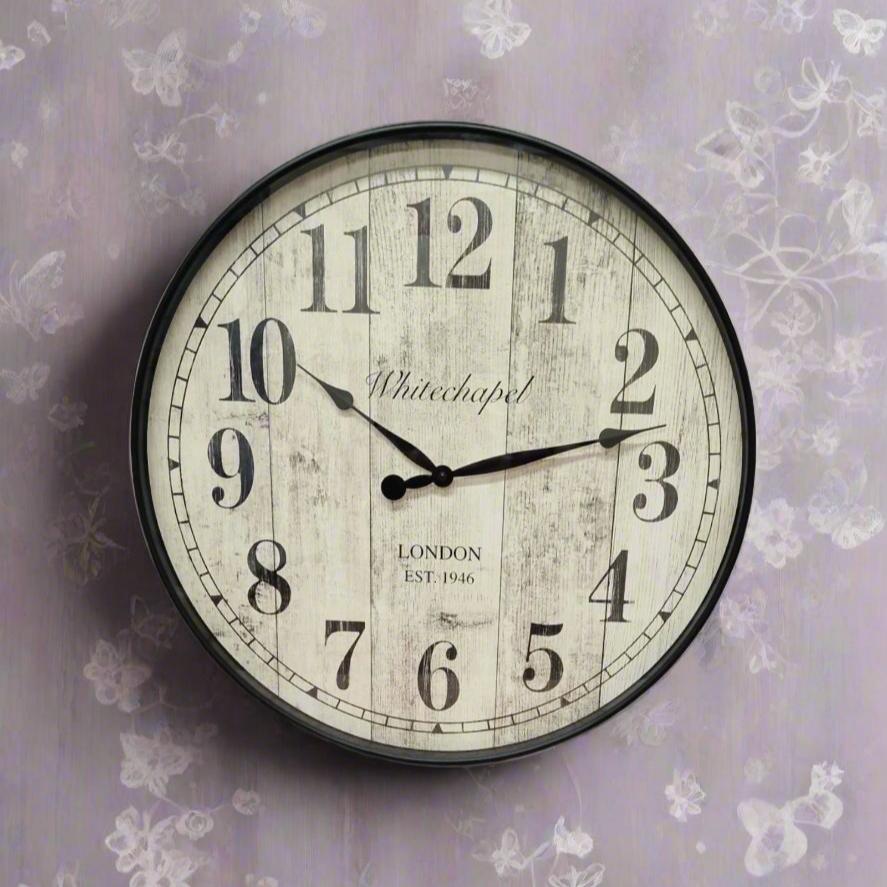 Antique round wall clock on a light pink, purple delicate flowers and butterflies and grey subtle wallpaper background with silver motifs of antique design