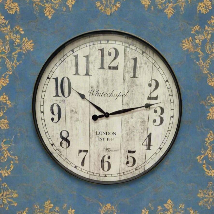 Round antique style wall clock on a background of pastel bule and delicate gold floral design wallpaper