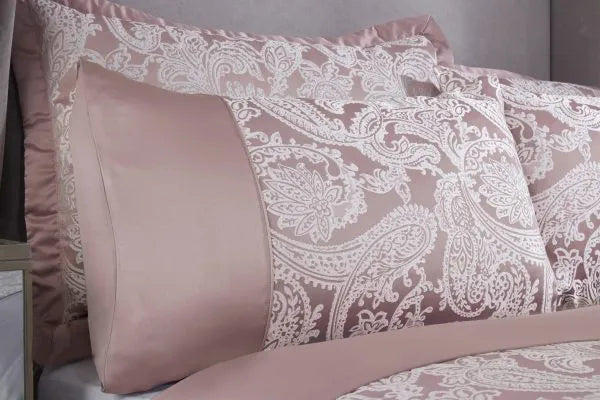 Close up of two pillows from a side view displaying the Duchess Collection Embellished Jacquard Duvet Double Bedding Cover Set in Blush Pink. Detailed paisley pattern displayed in white embroidery and a third of the pillow shows a plain sateen sheen material.